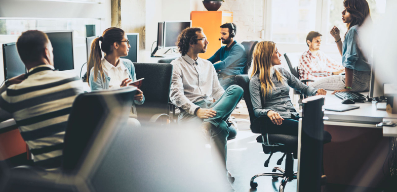 Business team in open plan office listening to co-worker