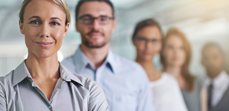 Office workers in a line, first woman in focus, all looking at camera