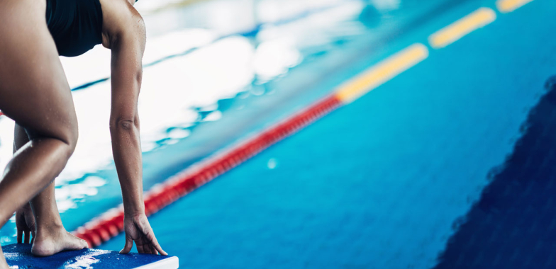 Female swimmer on the block ready to dive into the pool
