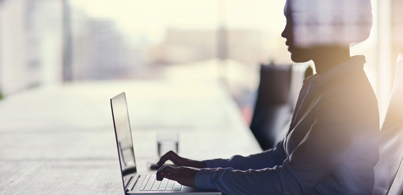 Woman sitting at a long table working on her laptop