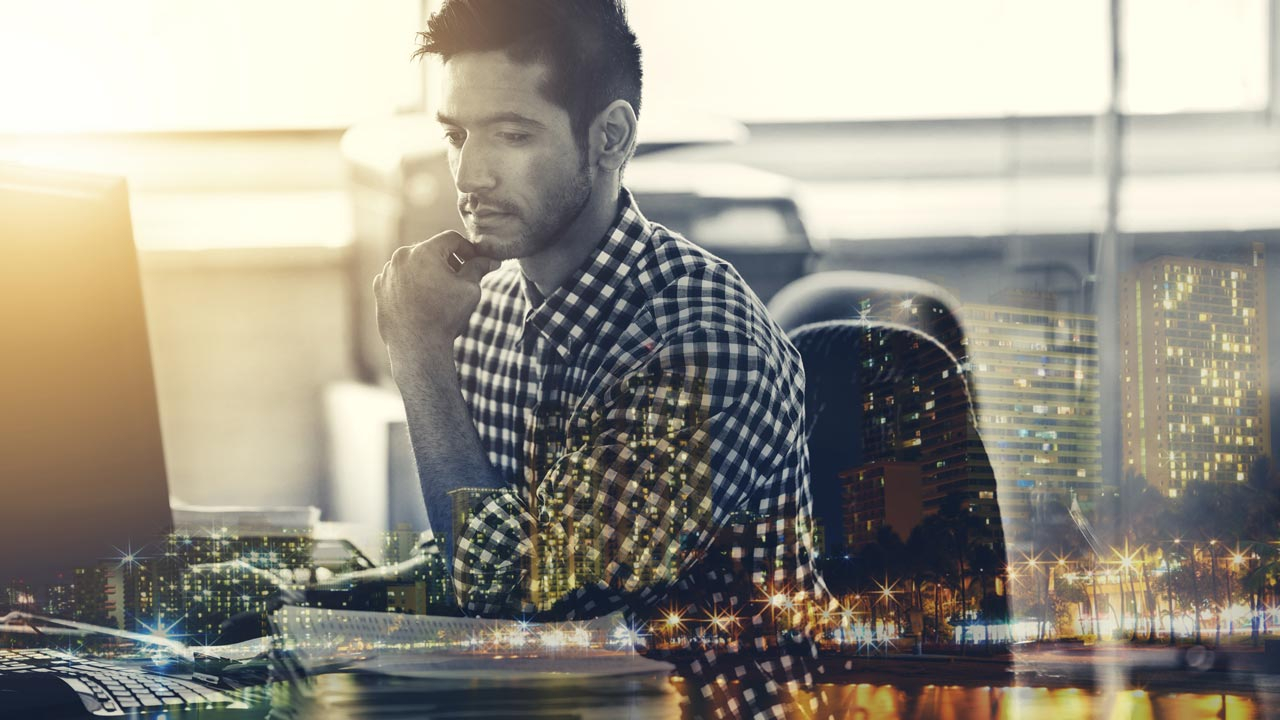 Man sitting in office in front of his computer thinking