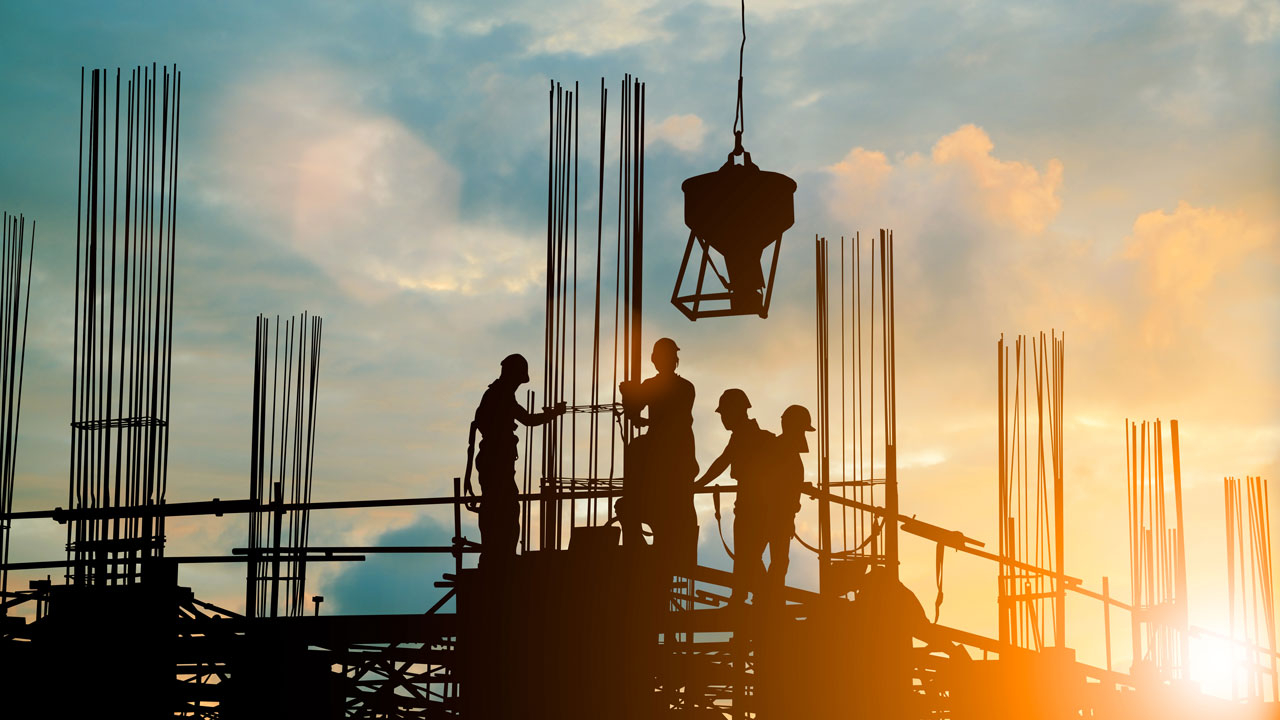 Construction workers on site at sunset