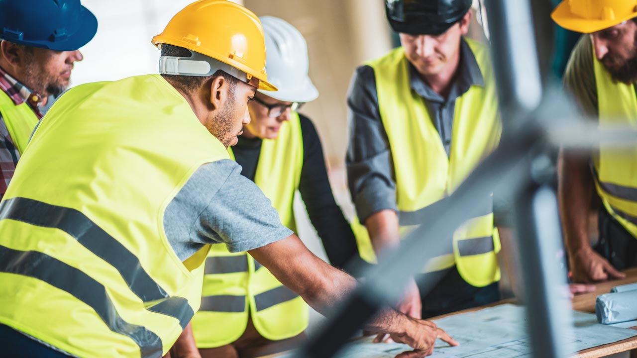 Building site workers around table looking at plans