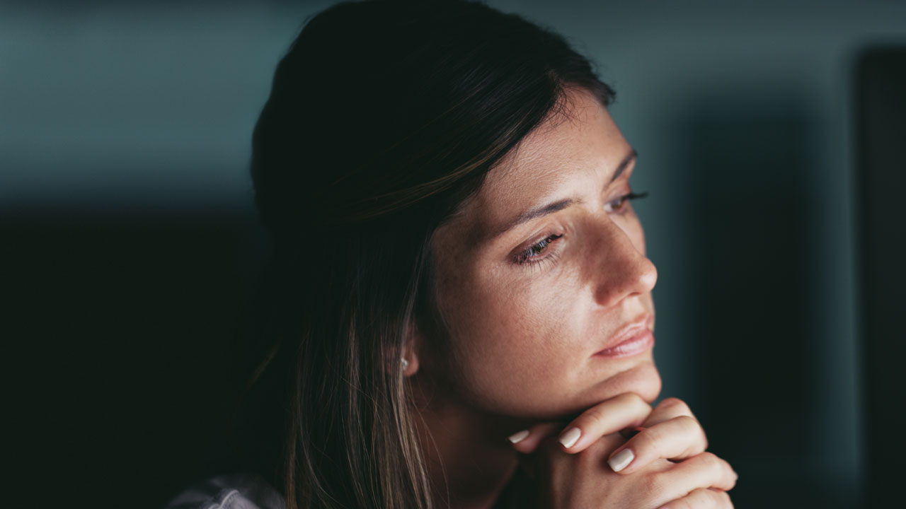 Close up of woman, chin on her hands looking thoughtfully to the right