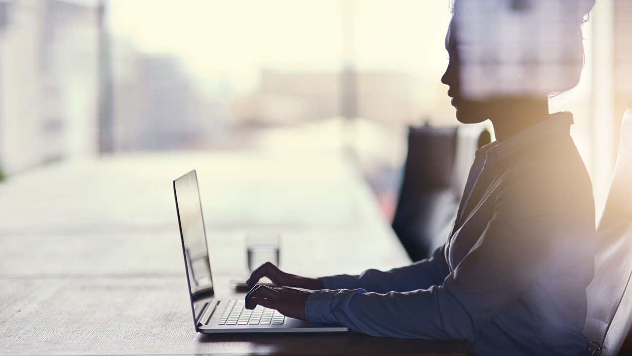 Woman sitting at a long table working on her laptop